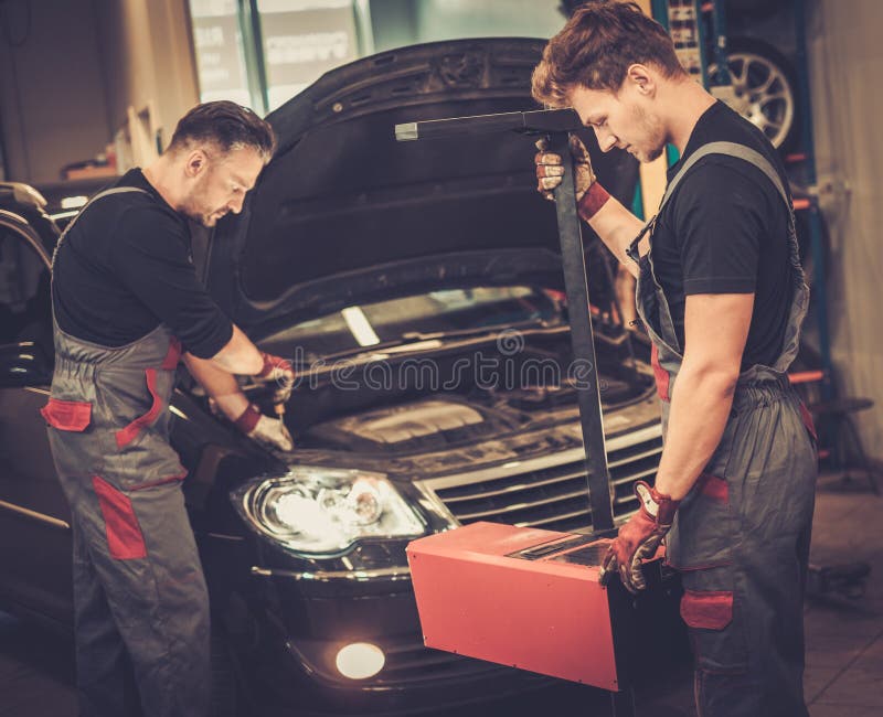 Professional car mechanics inspecting headlight lamp of automobile in auto repair service. Professional car mechanics inspecting headlight lamp of automobile in auto repair service.