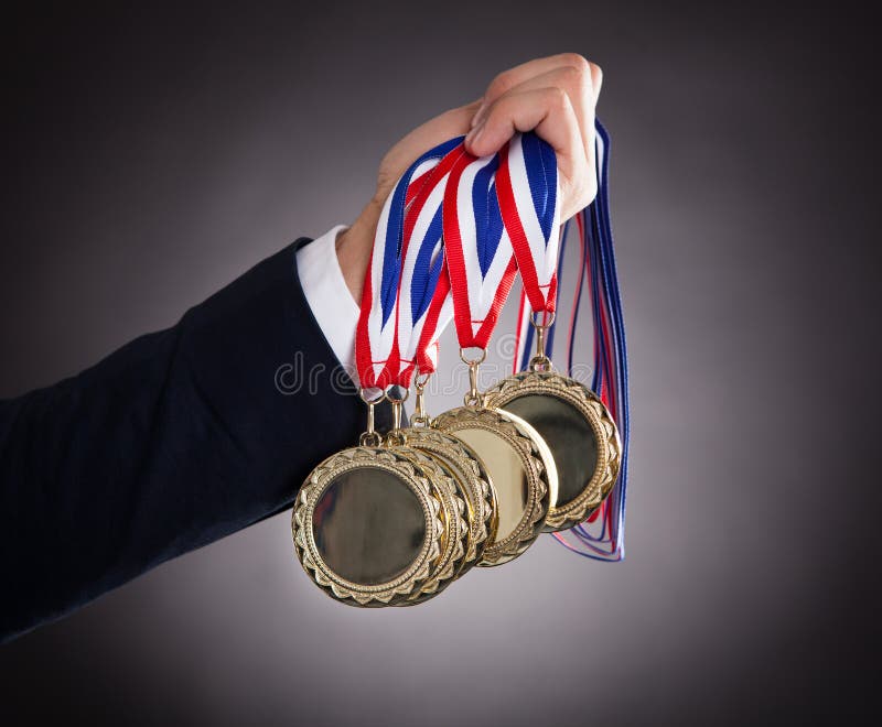 Medaglie d'oro della tenuta dell'uomo d'affari fotografie stock Medaglie d'oro della tenuta dell'uomo d'affari fotografie stock