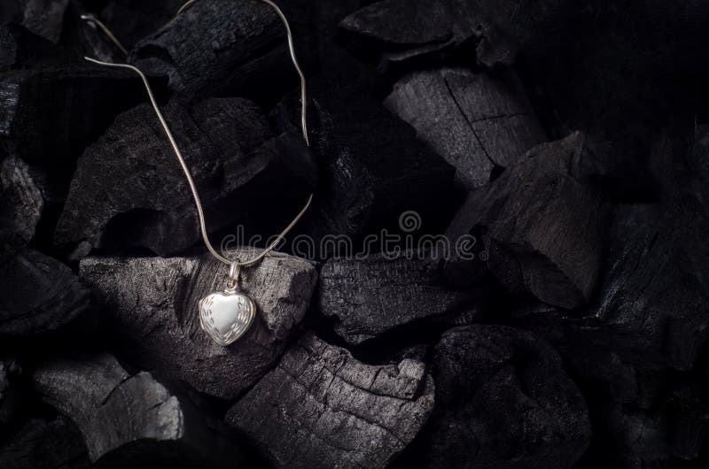 Silver heart shape locket with necklace on black charcoal texture background. Silver heart shape locket with necklace on black charcoal texture background