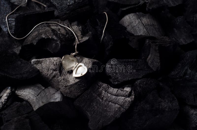 Silver heart shape locket with necklace on black charcoal texture background. Silver heart shape locket with necklace on black charcoal texture background