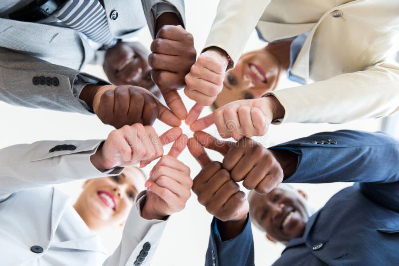 Low angle view of multiracial co-workers with thumbs joined together. Low angle view of multiracial co-workers with thumbs joined together