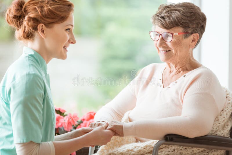 Medelevende verpleegster die geriatrisch gehandicapt geduldig w verklaren stock fotografie Medelevende verpleegster die geriatrisch gehandicapt geduldig w verklaren stock fotografie