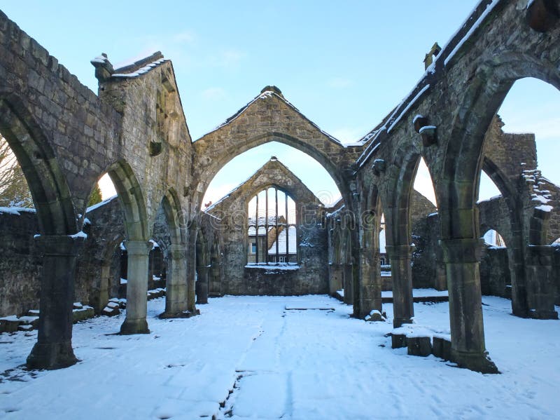 Medeltida förstörd kyrka i heptonstall som täckas i snö som visar bågar och kolonner mot en blå vinterhimmel royaltyfria bilder Medeltida förstörd kyrka i heptonstall som täckas i snö som visar bågar och kolonner mot en blå vinterhimmel royaltyfria bilder