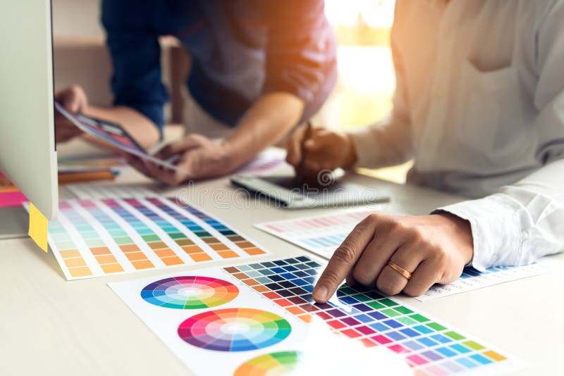 Medewerker grafische ontwerper die met vennootschap die kleur kiezen aan bureau in modern bureau werken stock afbeeldingen Medewerker grafische ontwerper die met vennootschap die kleur kiezen aan bureau in modern bureau werken stock afbeeldingen