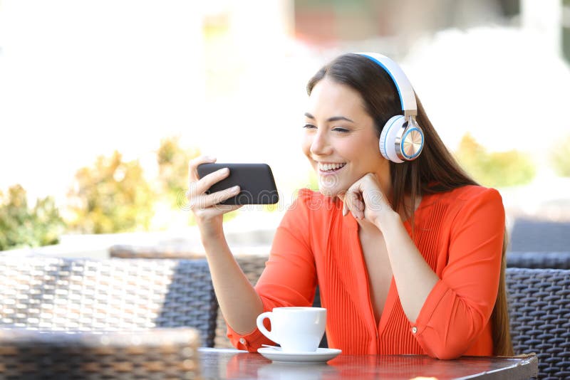 Media di sorveglianza della donna felice sullo Smart Phone in un ristorante immagini stock libere da diritti Media di sorveglianza della donna felice sullo Smart Phone in un ristorante immagini stock libere da diritti