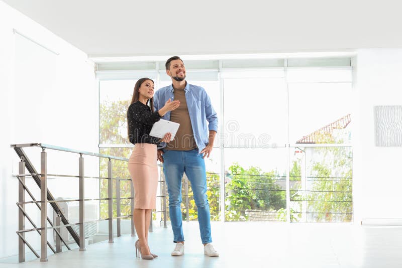 Mediador imobiliário fêmea que mostra a casa nova para equipar fotografia de stock Mediador imobiliário fêmea que mostra a casa nova para equipar fotografia de stock