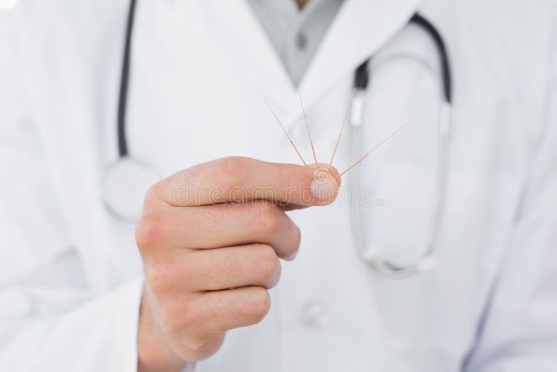 Mediados de sección de un doctor de sexo masculino que sostiene agujas de la acupuntura imagen de archivo Mediados de sección de un doctor de sexo masculino que sostiene agujas de la acupuntura imagen de archivo