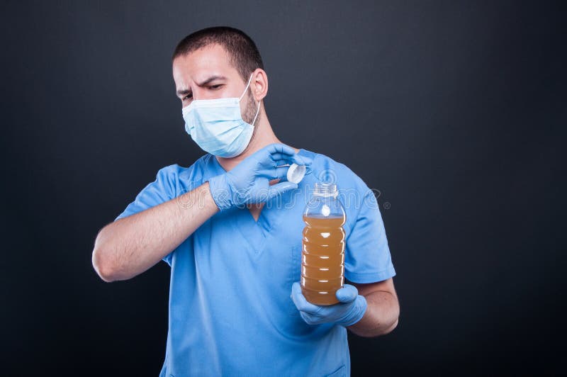 Medic wearing face mask holding bad smelling water stock images