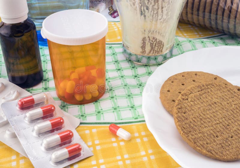 Medicación durante el desayuno, cápsulas al lado de un vaso de agua, imagen conceptual imagen de archivo libre de regalías Medicación durante el desayuno, cápsulas al lado de un vaso de agua, imagen conceptual imagen de archivo libre de regalías