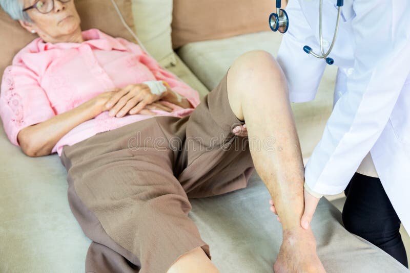 Medical asian doctor or nurse checking knee of senior patient in hospital bed or home,elderly woman receiving massage by female physic therapist of her leg due to injury,health care,support,checkup concept