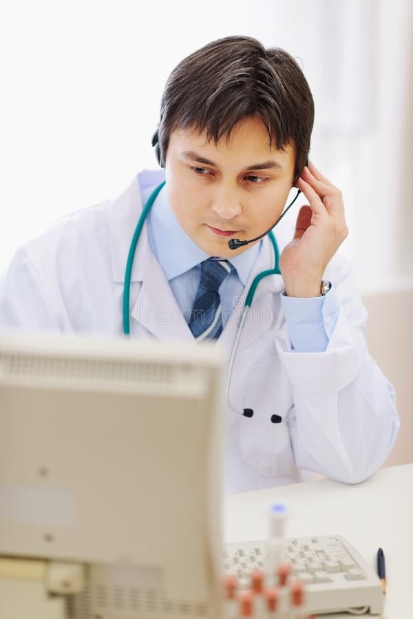 Medical doctor in headset working in office stock photo