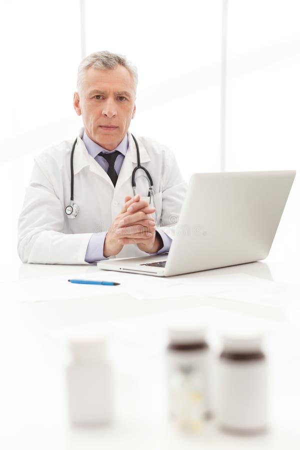 Medical Doctor.Mature Doctor Sitting at His Working Place with Stock