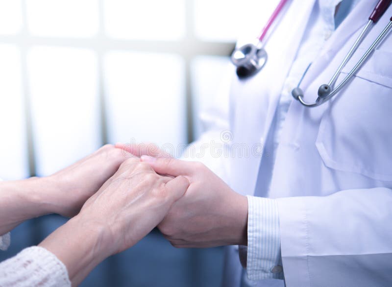 Medical doctor reassuring patient by holding patient’s hands in hospital setting royalty free stock photo Medical doctor reassuring patient by holding patient’s hands in hospital setting royalty free stock photo