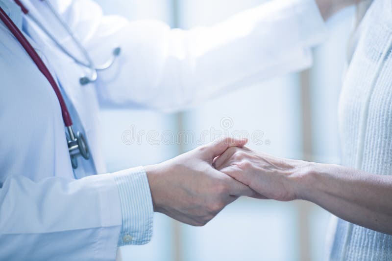 Medical doctor reassuring patient by holding patient’s hands in hospital setting royalty free stock photo Medical doctor reassuring patient by holding patient’s hands in hospital setting royalty free stock photo