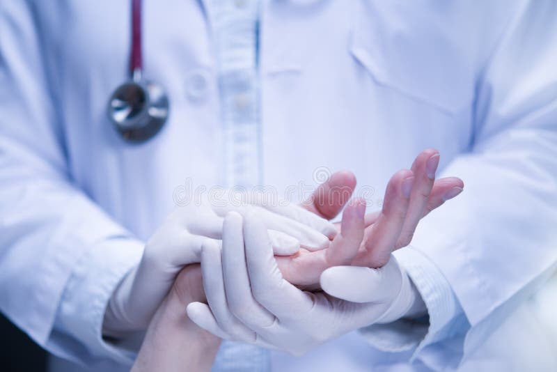 Medical doctor  wearing latex gloves holding patientâ€™s hand to give support in hospital setting