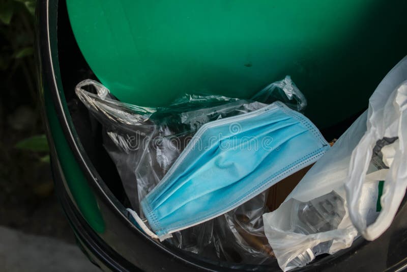 Medical face mask in the blue bin is full of trash. single use face mask. Right way to throwing used face mask in bin. Close up of