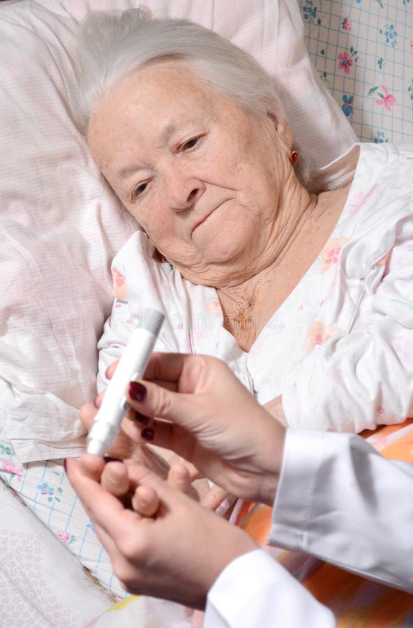 Medical nurse measuring the blood sugar level of old patient