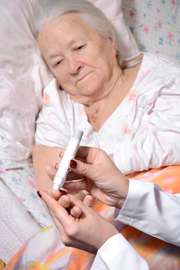 Medical nurse measuring the blood sugar level of old patient