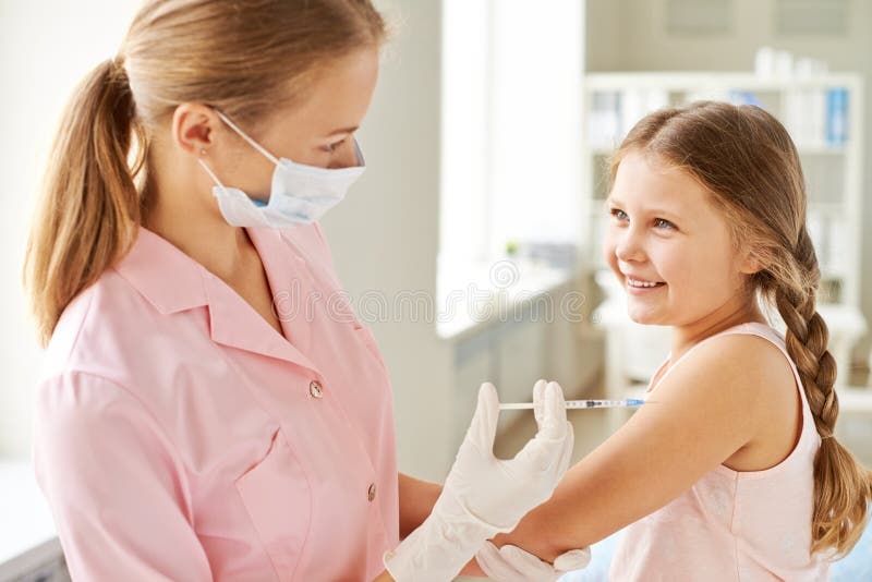 Adorable girl looking at nurse while she making her an injection in clinics. Adorable girl looking at nurse while she making her an injection in clinics