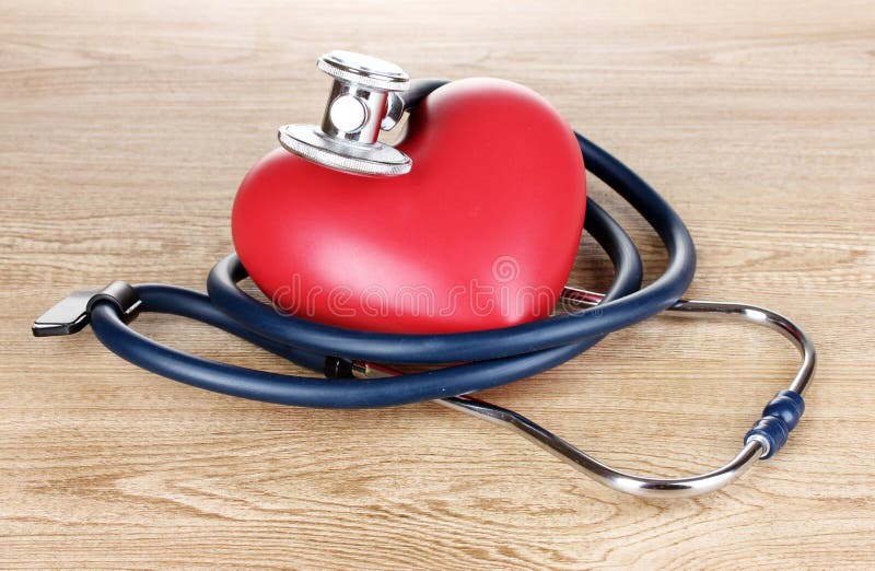 Medical stethoscope and heart on wooden