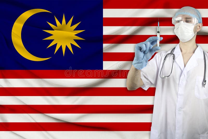 Medical syringe for injection in the hands of a doctor against the background of the Malaysia national flag, concept of stock photos Medical syringe for injection in the hands of a doctor against the background of the Malaysia national flag, concept of stock photos