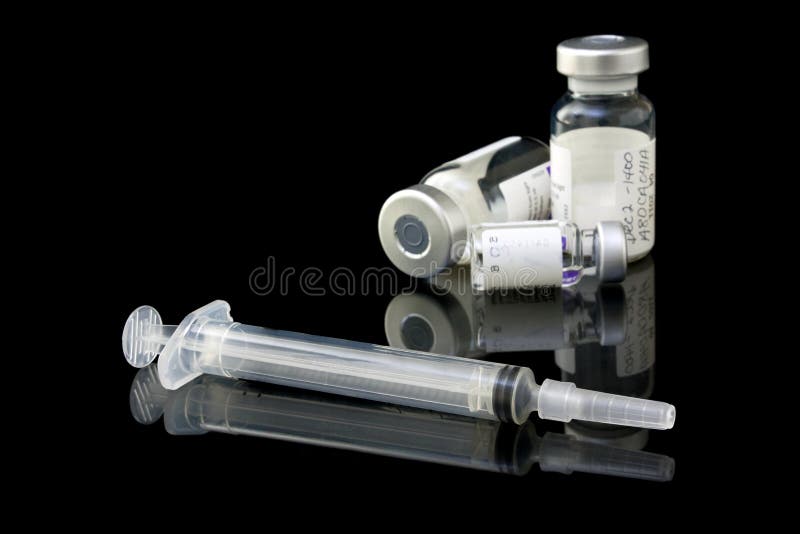 A set of medical vaccine vials and syringe on a black background. A set of medical vaccine vials and syringe on a black background