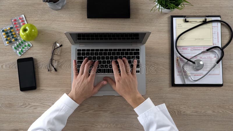 Medical worker typing on laptop, keeping electronic medical records, top view