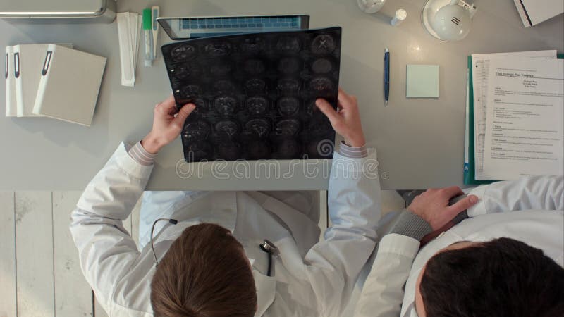 Medici team avendo una discussione ed esaminano un imaging a risonanza magnetica Vista superiore immagini stock libere da diritti Medici team avendo una discussione ed esaminano un imaging a risonanza magnetica Vista superiore immagini stock libere da diritti