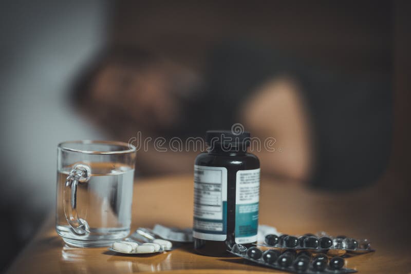Medicina, comprimidos, vidro da água A pessoa que est?o com a gripe, a febre e a dor de cabe?a no sof? deitam Frio travado no inv foto de stock Medicina, comprimidos, vidro da água A pessoa que est?o com a gripe, a febre e a dor de cabe?a no sof? deitam Frio travado no inv foto de stock