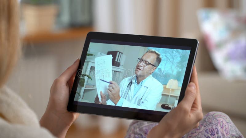 Medicina en línea Mujer joven que consulta con su doctor usando la charla video en casa