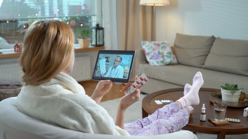 Medicina en línea Mujer joven que consulta con su doctor usando la charla video en casa