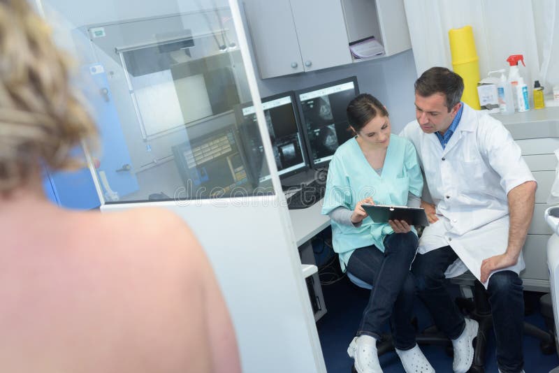Medicinsk personal för radiologi i naken skuldra för diskussionspatienter i förgrund fotografering för bildbyråer Medicinsk personal för radiologi i naken skuldra för diskussionspatienter i förgrund fotografering för bildbyråer