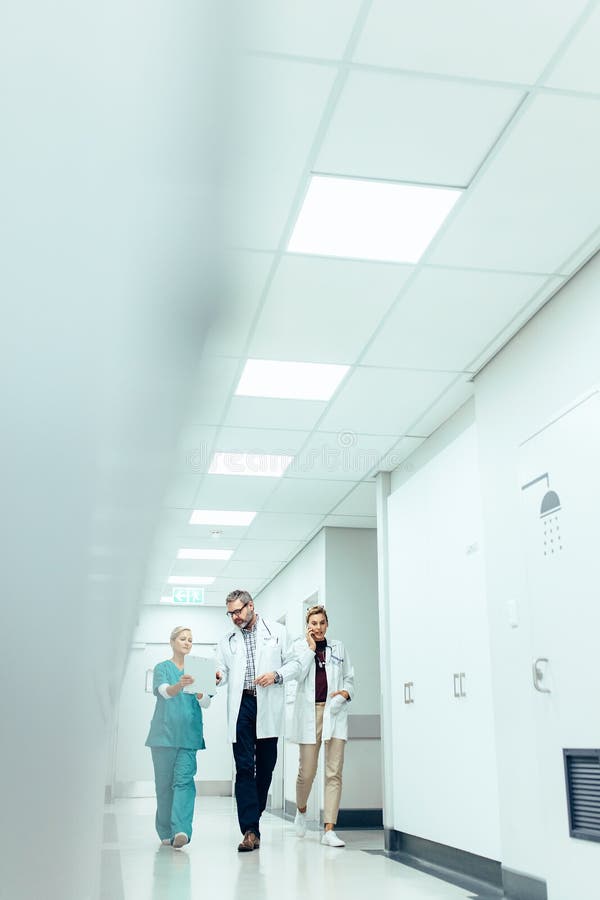 Medicinskt lag i sjukhuskorridor som diskuterar arbete royaltyfri foto Medicinskt lag i sjukhuskorridor som diskuterar arbete royaltyfri foto