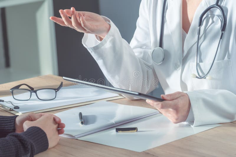 Medico che consiglia paziente nell'ufficio dell'ospedale fotografia stock Medico che consiglia paziente nell'ufficio dell'ospedale fotografia stock