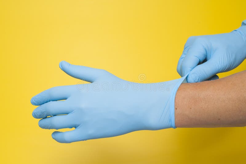 Medico che indossa i guanti blu protettivi isolati su fondo giallo immagini stock libere da diritti Medico che indossa i guanti blu protettivi isolati su fondo giallo immagini stock libere da diritti