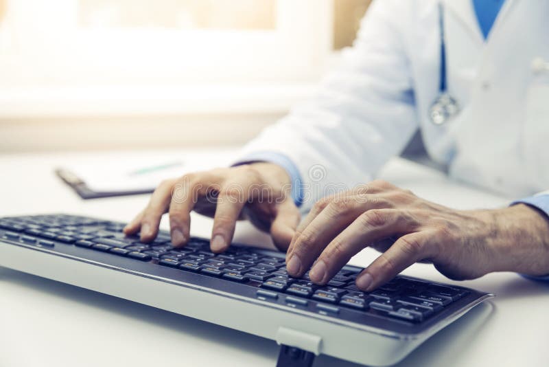Medico che scrive sulla tastiera di computer in ufficio consultatio online fotografia stock Medico che scrive sulla tastiera di computer in ufficio consultatio online fotografia stock