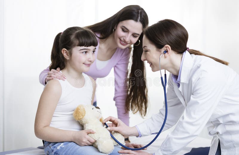 Medico che visita una ragazza sveglia e che gioca con lei fotografia stock Medico che visita una ragazza sveglia e che gioca con lei fotografia stock