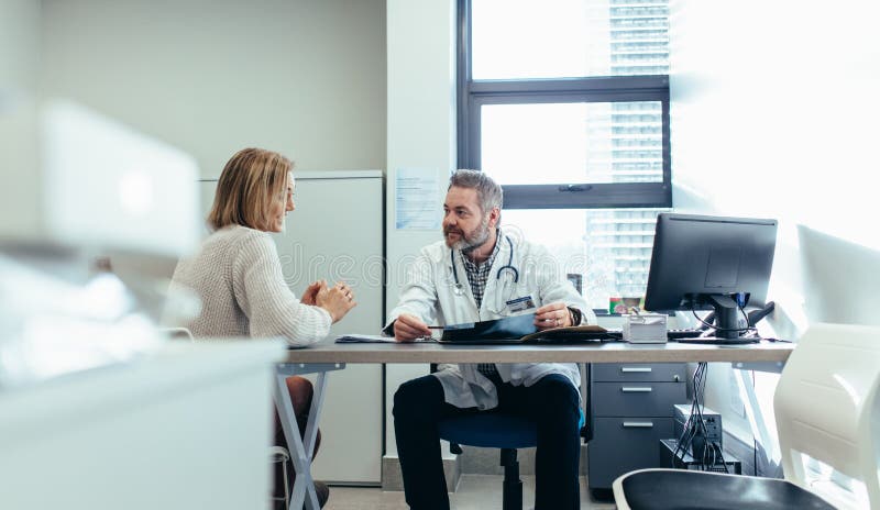 Medico con il paziente durante la consultazione in ufficio medico immagine stock libera da diritti Medico con il paziente durante la consultazione in ufficio medico immagine stock libera da diritti