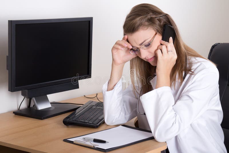Medico della donna sollecitato giovani che si siede nell'ufficio fotografia stock libera da diritti Medico della donna sollecitato giovani che si siede nell'ufficio fotografia stock libera da diritti