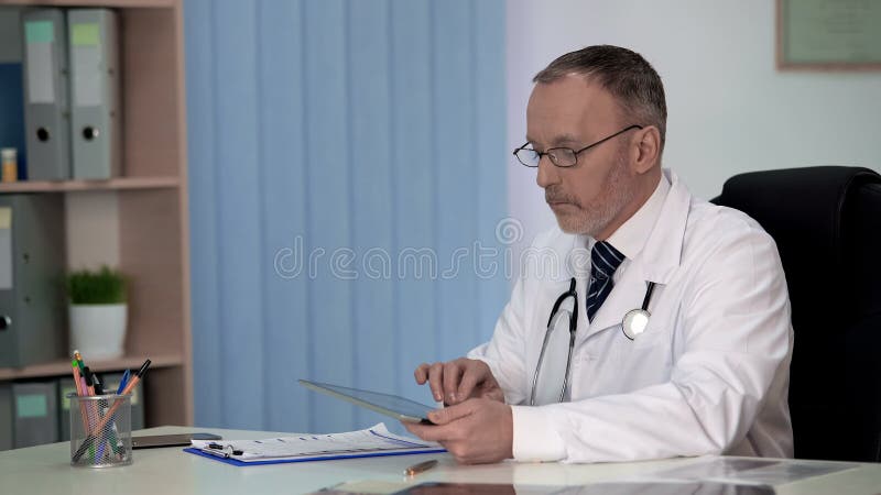Medico di famiglia che tiene le cartelle sanitarie elettroniche, medicina contemporanea fotografia stock Medico di famiglia che tiene le cartelle sanitarie elettroniche, medicina contemporanea fotografia stock