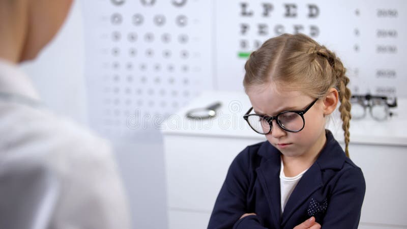 Medico donna che mette gli occhiali su una ragazza contrariata, il bambino si sente insicuro, sconvolto