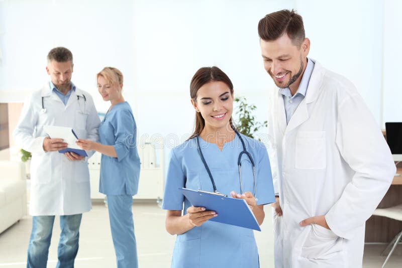 Medico ed assistente medico con i colleghi in clinica fotografie stock libere da diritti Medico ed assistente medico con i colleghi in clinica fotografie stock libere da diritti