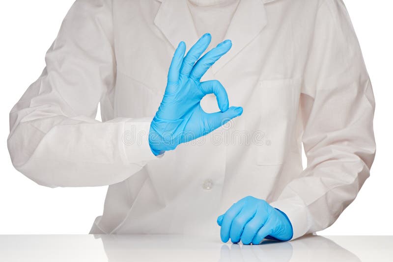 Medico femminile in abito ed in blu medici bianchi ha sterilizzato i guanti chirurgici che mostrano il segno GIUSTO fotografie stock libere da diritti Medico femminile in abito ed in blu medici bianchi ha sterilizzato i guanti chirurgici che mostrano il segno GIUSTO fotografie stock libere da diritti