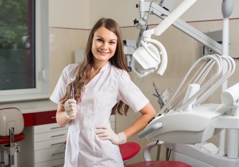 Medico femminile attraente con il microscopio nell'ufficio moderno del dentista immagine stock Medico femminile attraente con il microscopio nell'ufficio moderno del dentista immagine stock