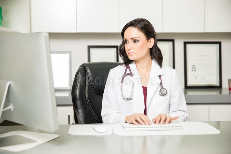 Medico femminile che lavora nel suo ufficio fotografia stock Medico femminile che lavora nel suo ufficio fotografia stock