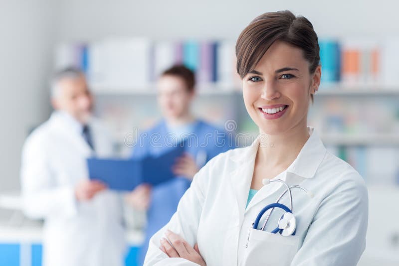 Medico femminile che posa nell'ufficio fotografia stock Medico femminile che posa nell'ufficio fotografia stock