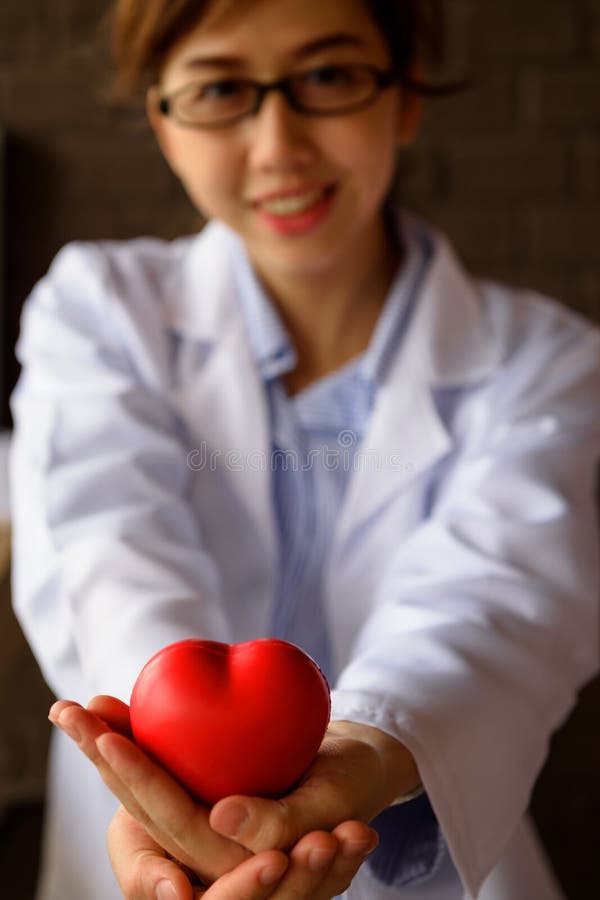 Medico femminile con cuore rosso a disposizione fotografia stock Medico femminile con cuore rosso a disposizione fotografia stock