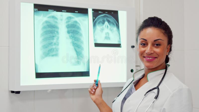 Medico femminile indica la penna sulla spina dorsale sull'immagine dei raggi x fotografia stock Medico femminile indica la penna sulla spina dorsale sull'immagine dei raggi x fotografia stock
