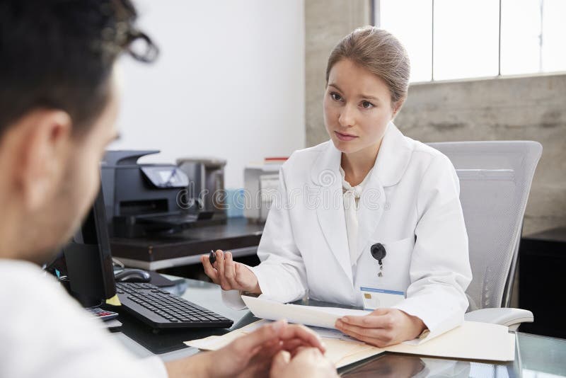 Medico femminile interessato in consultazione con il paziente maschio fotografia stock libera da diritti Medico femminile interessato in consultazione con il paziente maschio fotografia stock libera da diritti