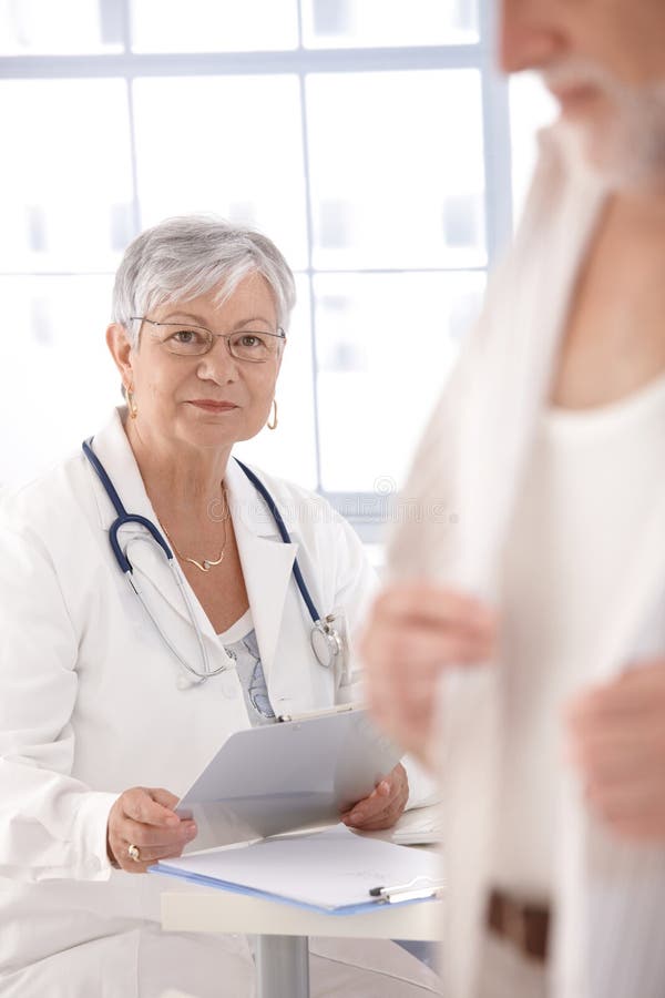 Medico femminile maggiore che esamina paziente immagini stock libere da diritti Medico femminile maggiore che esamina paziente immagini stock libere da diritti